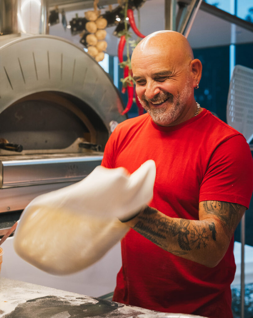 Person beim vorbereiten von Pizzateig.