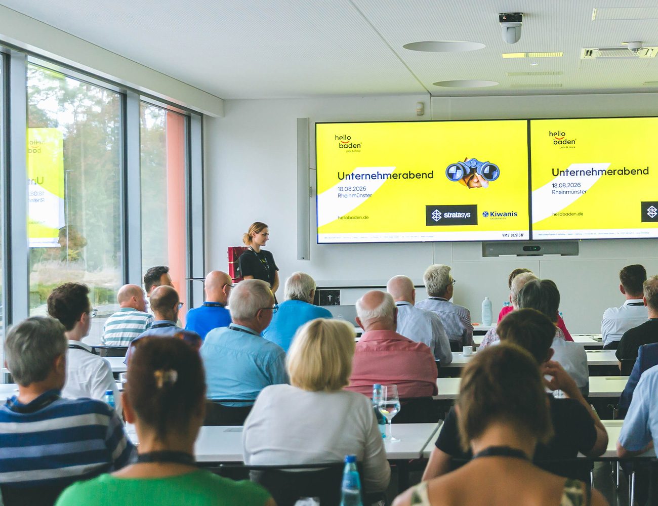 Personen schauen auf einen Bildschirm mit einer Präsentation.