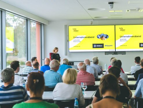 Personen schauen auf einen Bildschirm mit einer Präsentation.