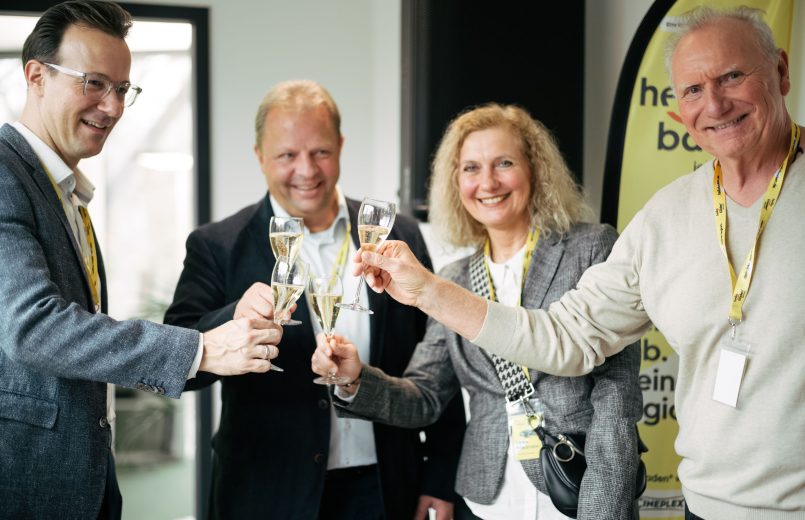 Personen stoßen mit Sektgläsern zusammen an auf dem Kick-off Event von hello baden