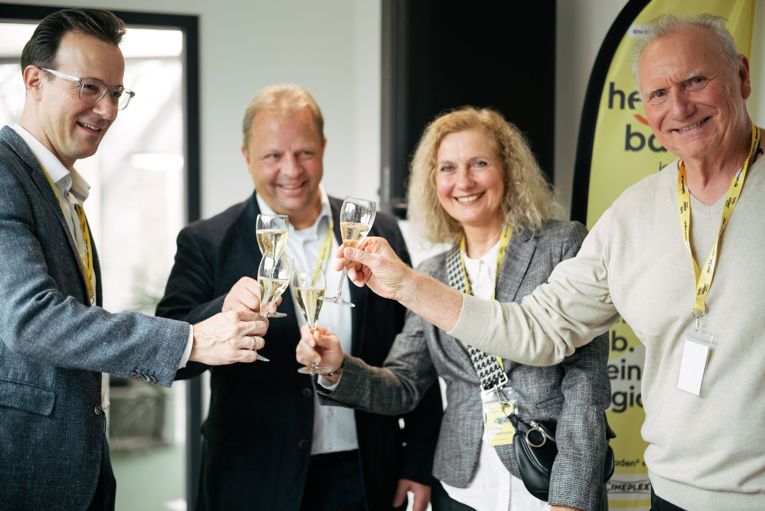Personen stoßen mit Sektgläsern zusammen an auf dem Kick-off Event von hello baden