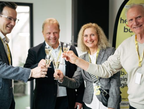 Personen stoßen mit Sektgläsern zusammen an auf dem Kick-off Event von hello baden